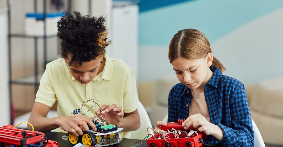 Two teenagers collaborating on a robotics project, focusing on circuitry and innovation.